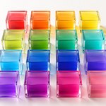 Sixteen translucent glass containers arranged in a tidy grid, their colours running in colour-wheel order